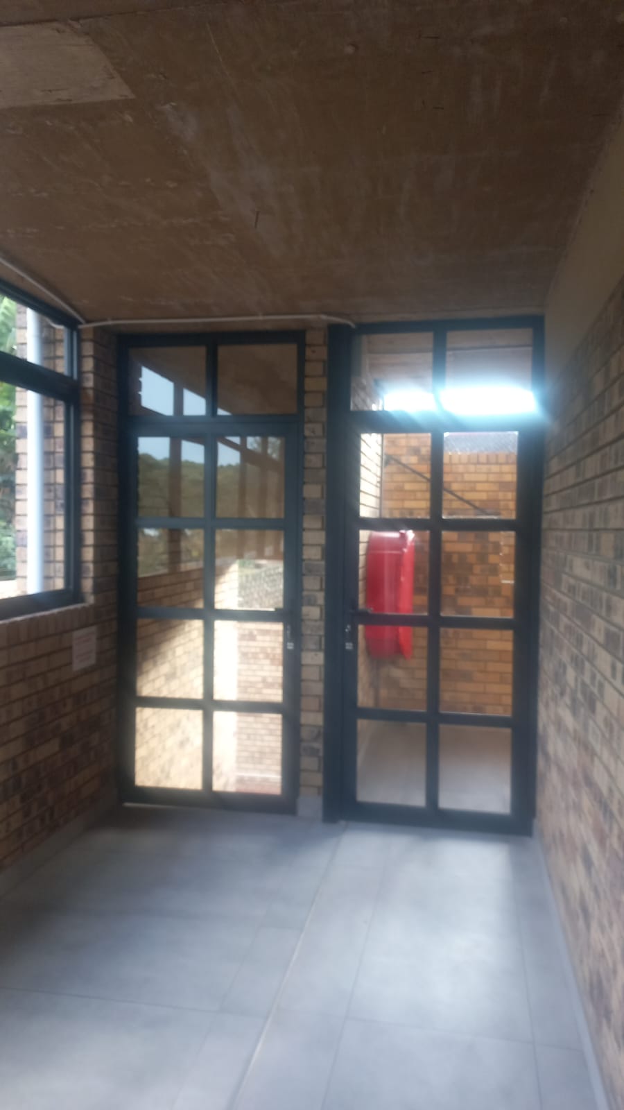 Dark aluminium doors in a brick corridor