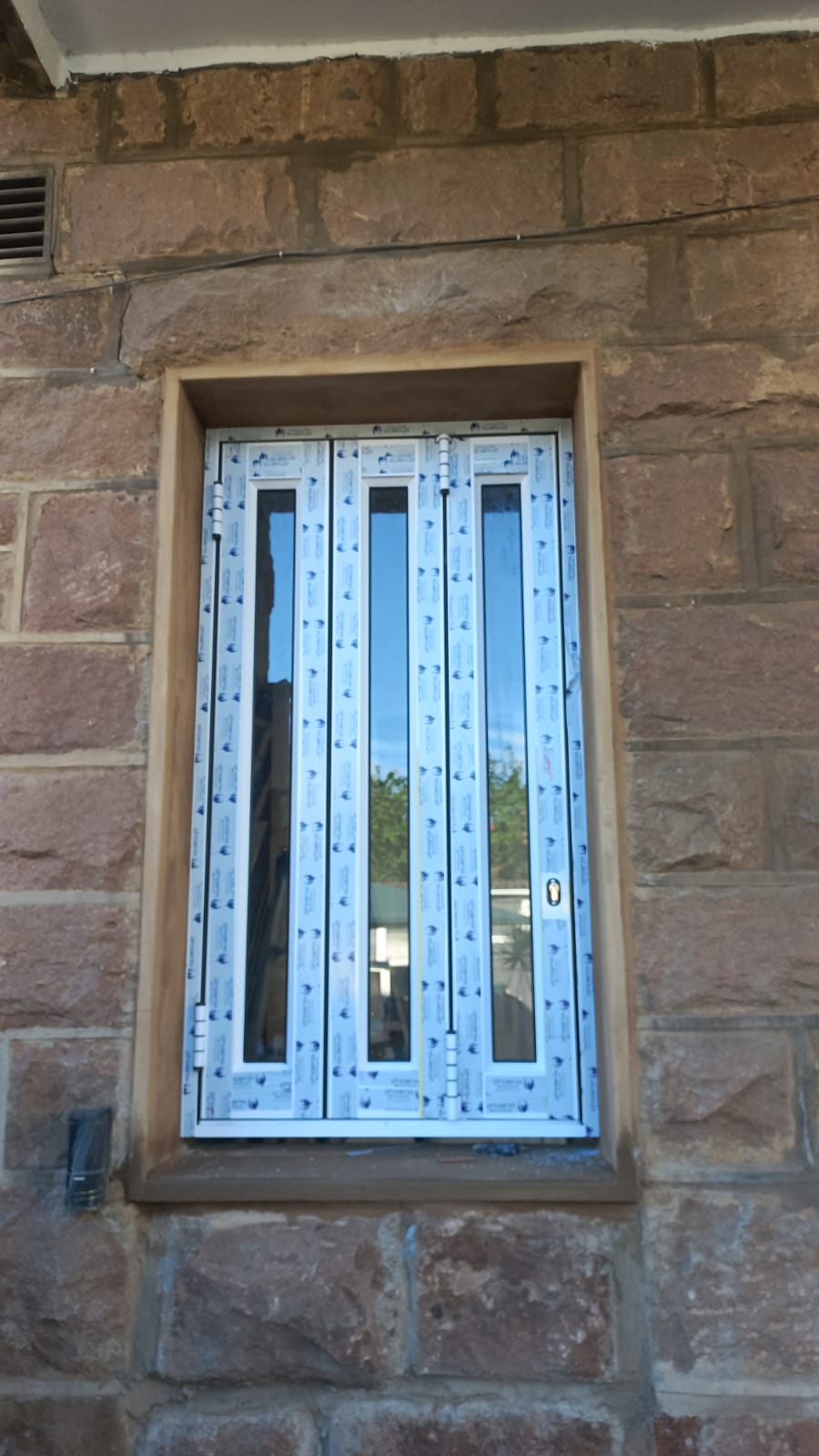 White aluminium folding window installed in stone wall