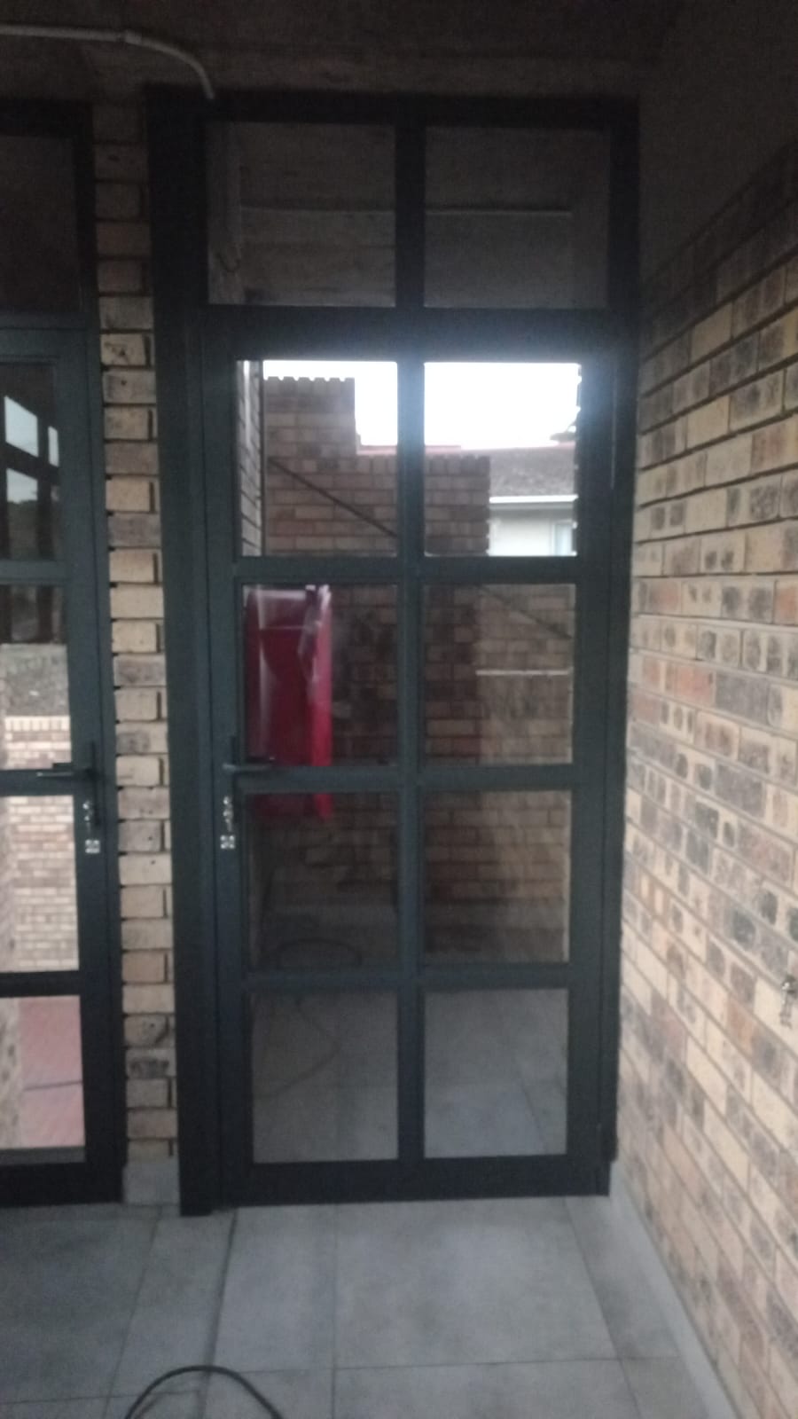 Dark framed aluminium glass door in a brick corridor