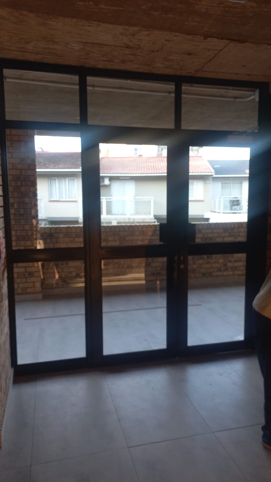 Dark-framed aluminium glass doors in a brick corridor