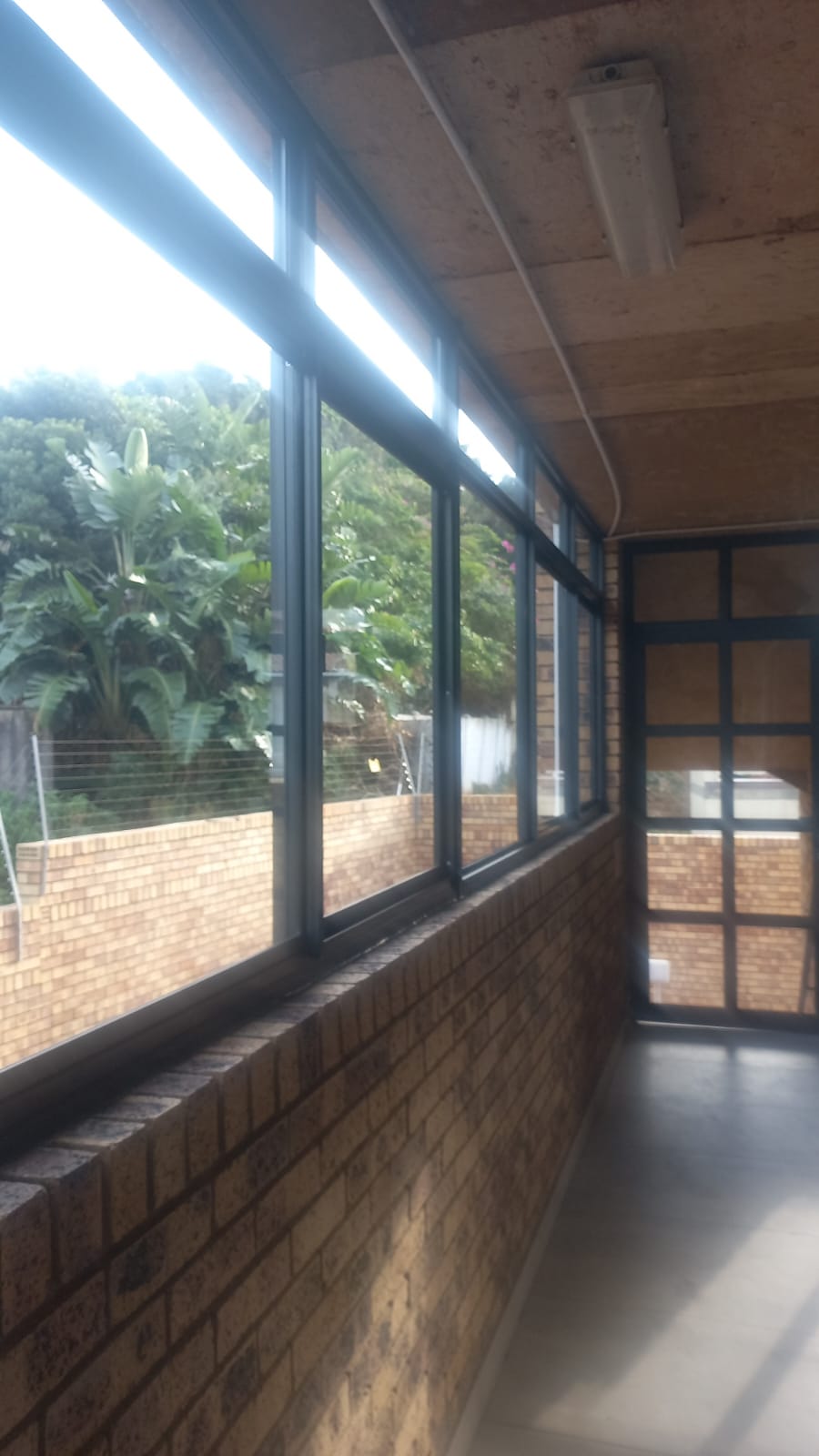 Aluminium windows along a covered brick corridor