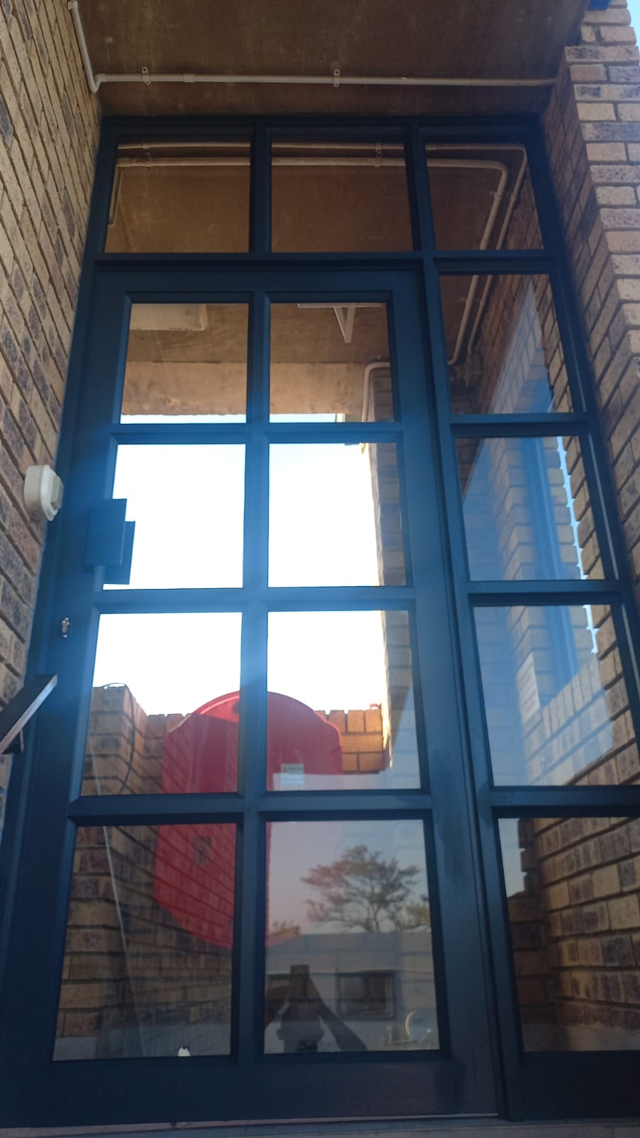 Tall dark-framed aluminium window in a brick building